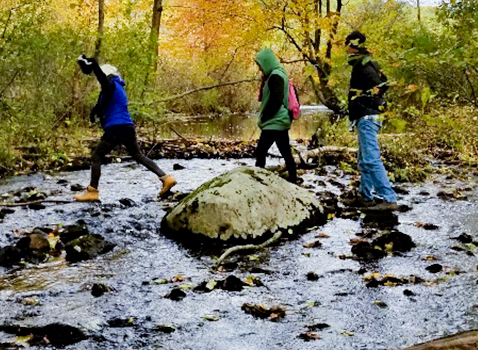 3 people hiking across a rocky creek